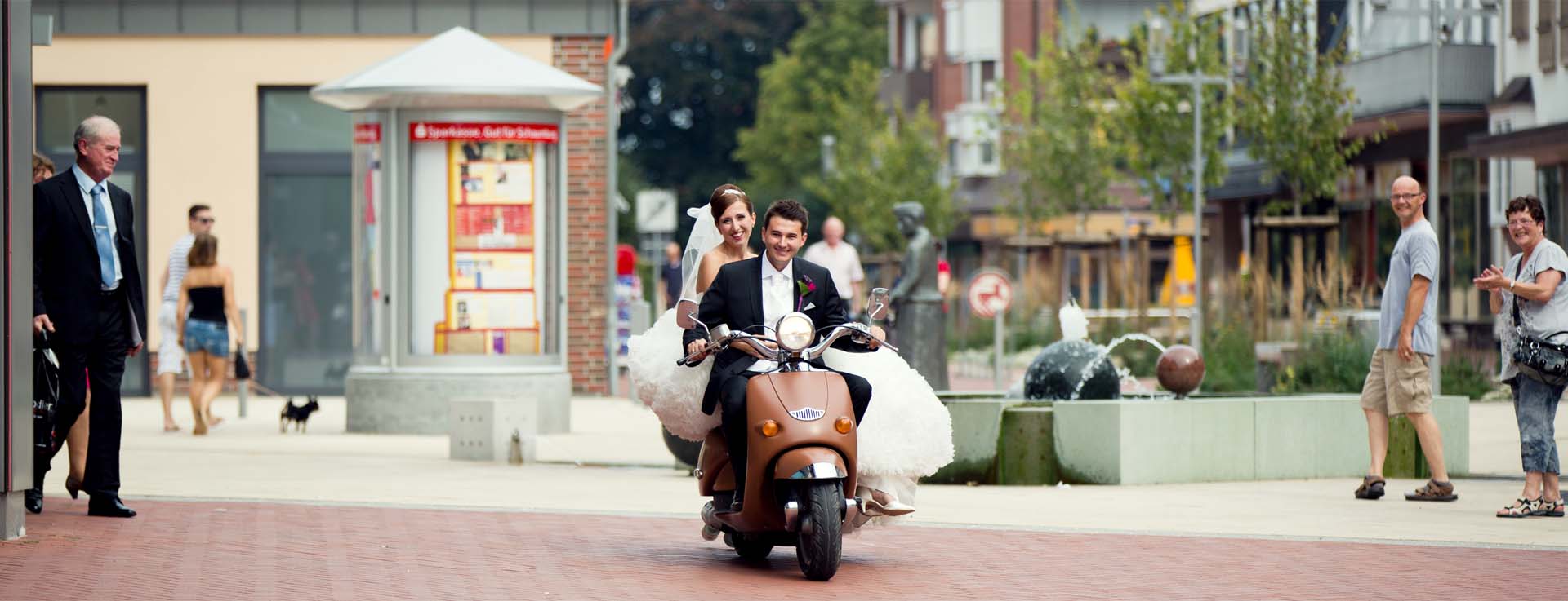 Brautpaar auf einem Mofa fahren durch die City