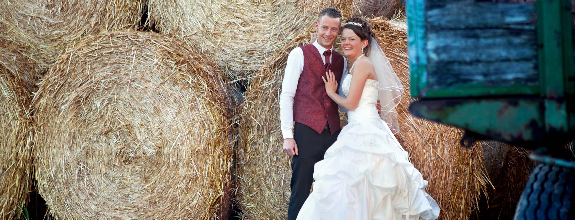 Landhochzeit, ein Brautpaar mit Strohballen und Traktor