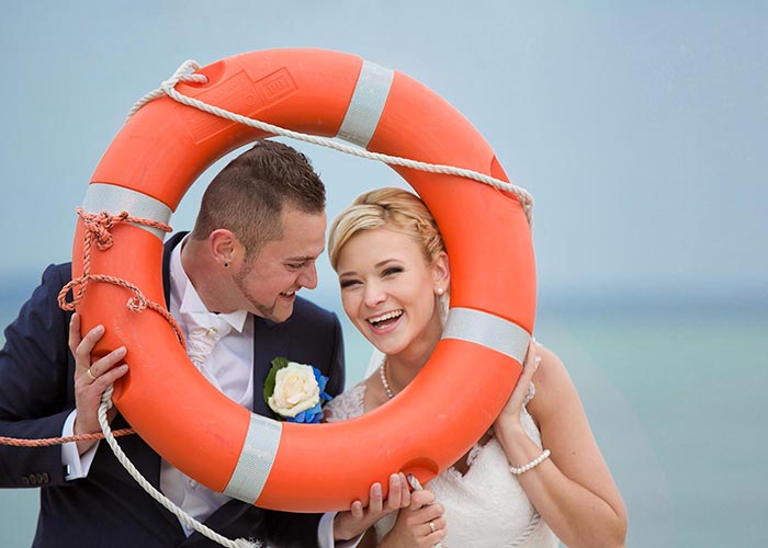 Portrait vom lachenden Brautpaar am Ostsee mit Rettungsring